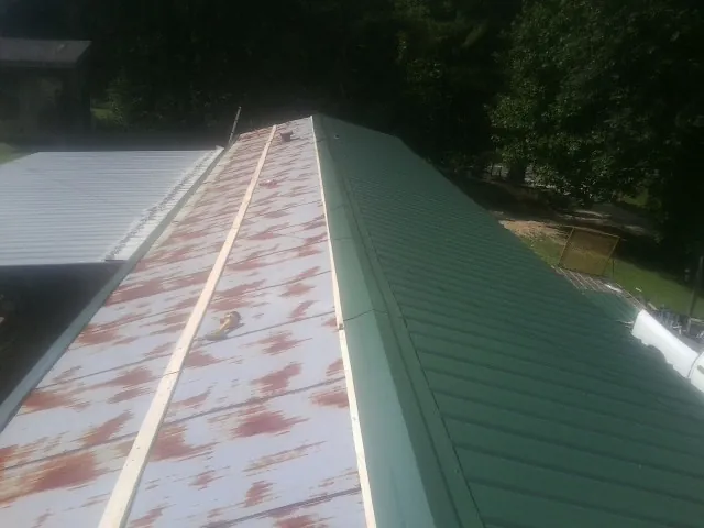Old rusted panels beside newly installed green metal roofing — Wind Damage Roof Repair by Roofing Brothers in Mountainville