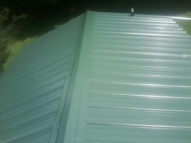 New green metal panels meeting at the ridge of a roof — Flat Roof Repair work by our crew in Mountainville
