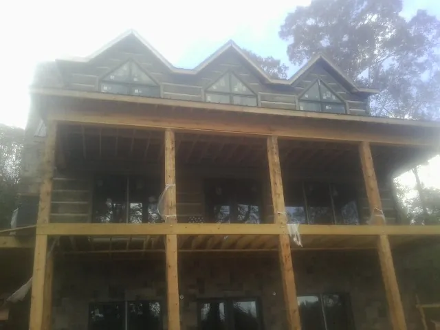 Dormers and porch framing on a large log home under construction — Roof Coating work by our crew in Mountainville