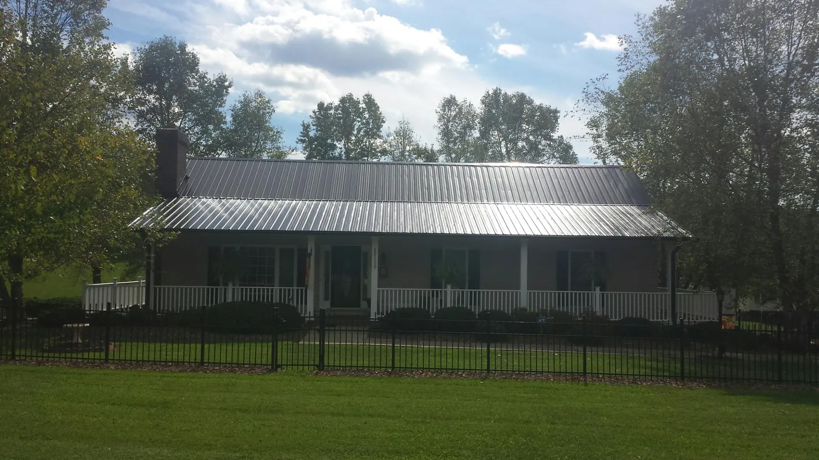 Gray metal roof on a brick ranch with a full width front porch — Gutter Guard Installation work by our crew in Mountainville