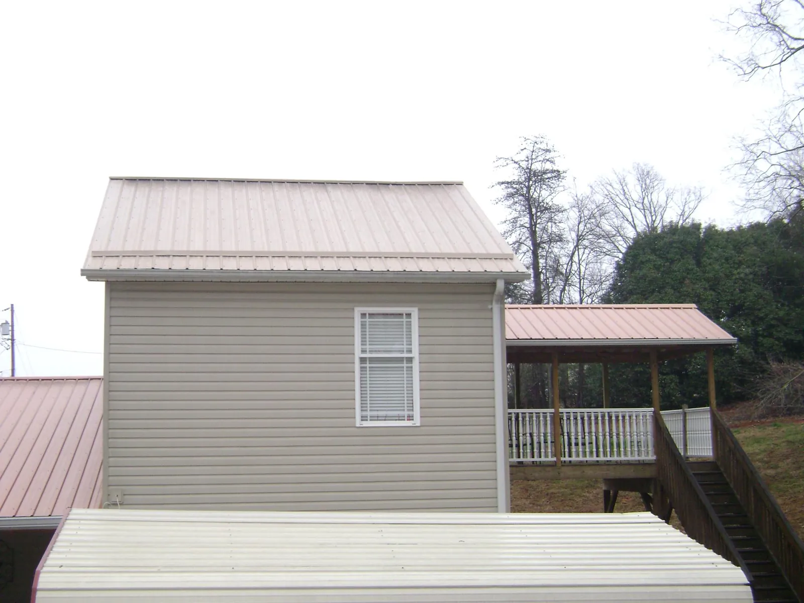 Tan metal roofs on a two story addition and attached porch, from a Roof Replacement job in Mountainville
